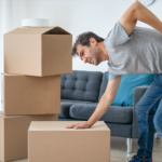 A man is having backache while lifting moving boxes
